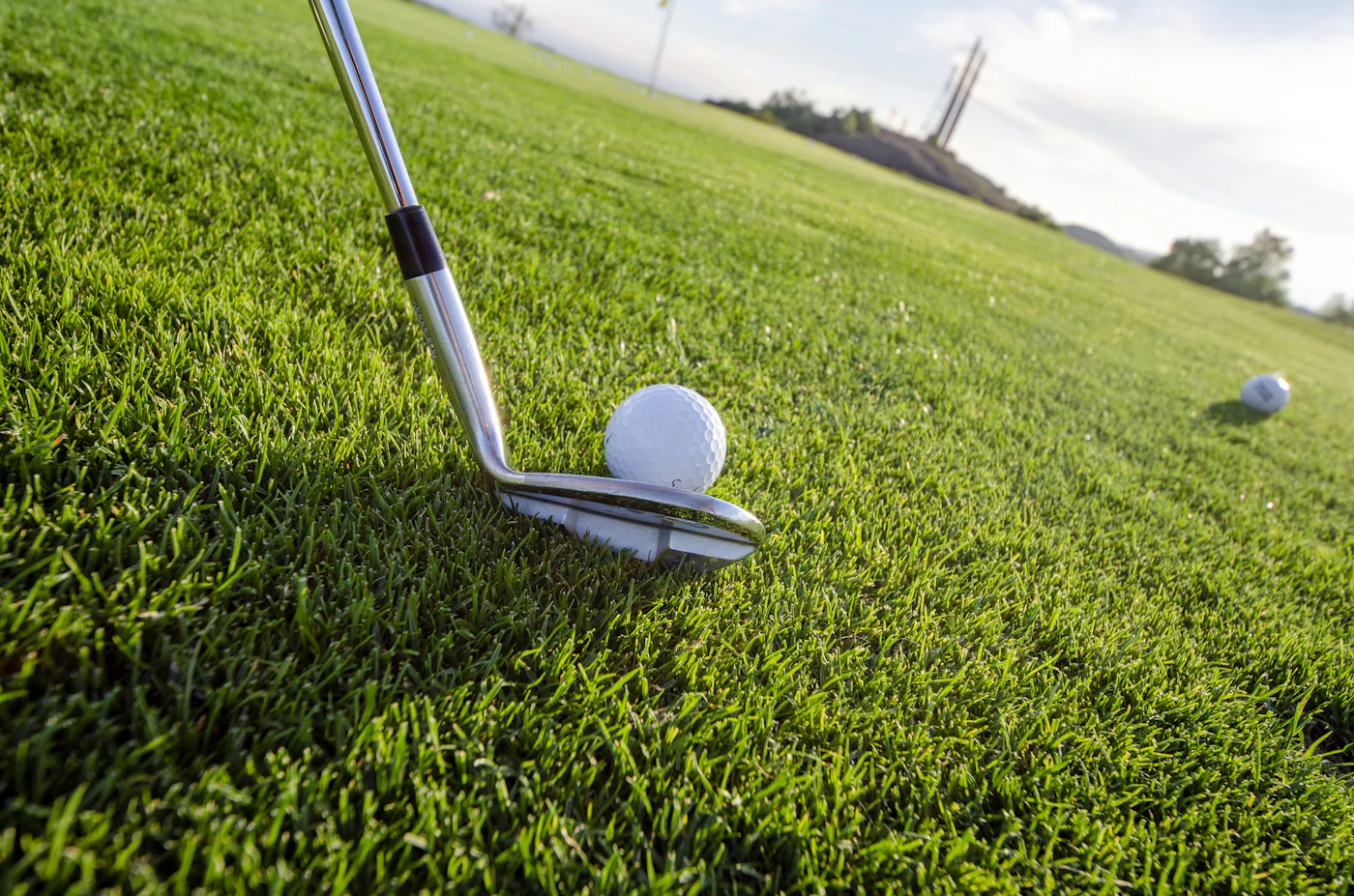 Iron positioned behind a golf ball on short grass