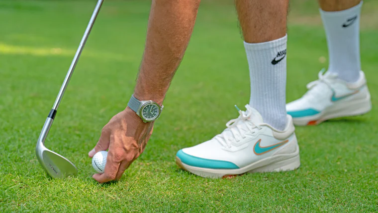 Golfer playing a wedge shot from short grass